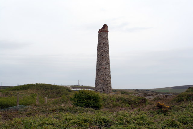 A tall round stone chimney with a broken top standing alone in scrubby heath near Leswidden.