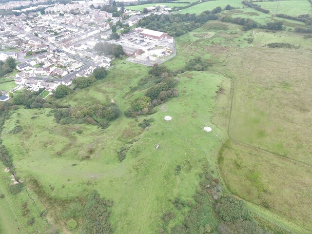 Aerial view of the former Barrow Collieries site: two white-marked capped mine shafts with the line of a former railway siding between them, running into the adjoining brickyard.