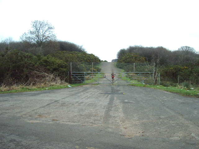 A gated and fenced entrance to the disused Boaterby gypsum quarry beside a country road near Cotehill