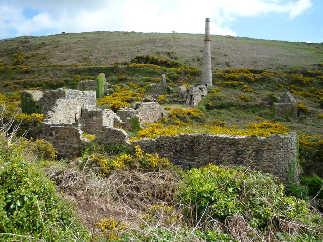 Roofless stone mine buildings among gorse on a hillside at Boscean, with a tall chimney behind.