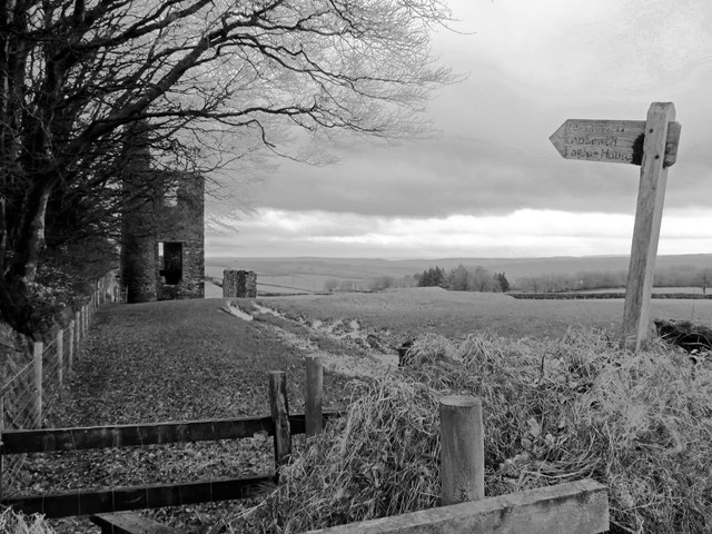 The roofless stone engine house at Burrow Farm Mine on the Brendon Hills, its circular chimney standing full height against the north wall, seen from the permissive path across rough pasture.