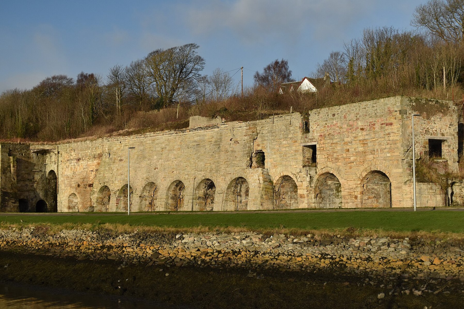 The long dressed-stone range of limekilns at Charlestown on the Firth of Forth, built into the slope above the harbour, with the arched draw holes of eleven kilns visible