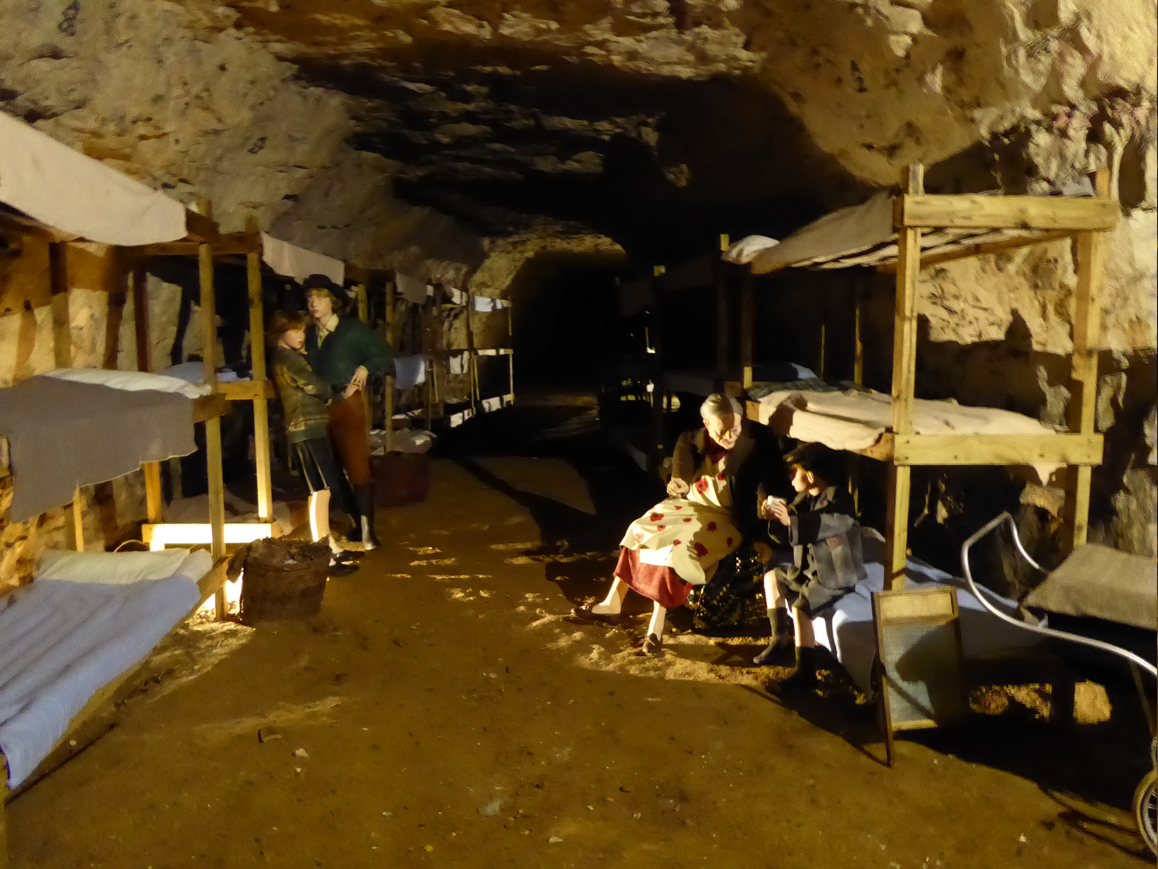 A reconstructed wartime dormitory in the chalk tunnels, with bunk beds set against the rough cut walls.