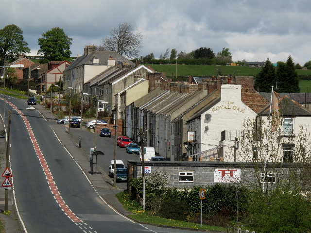 Stone terraced houses along the road through Cornsay Colliery, with open County Durham countryside beyond.