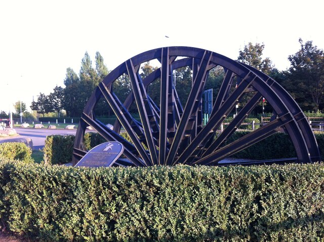 A large pit winding wheel from Coventry Colliery, mounted as a memorial at the entrance to Prologis Park, Keresley, commemorating the colliery's workers.