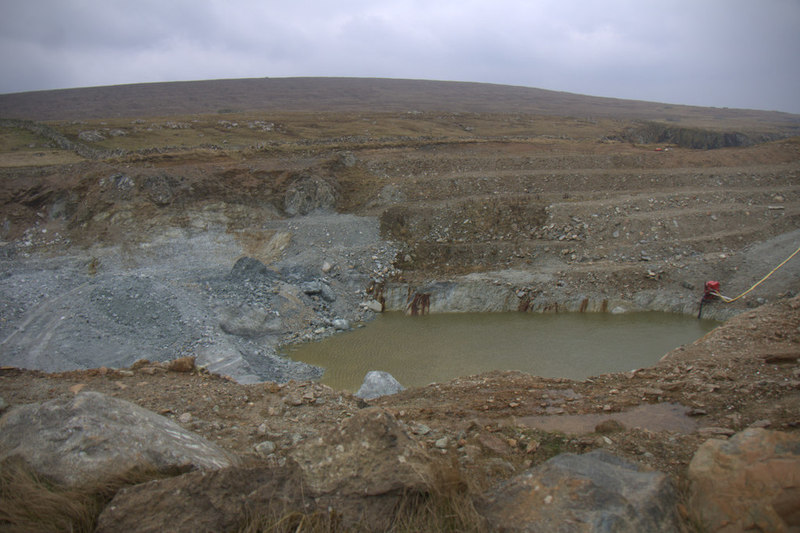 A grey-green talc quarry cut into the cliff and foreshore at Cross Geo, Clibberswick, Unst, partly filled with water.