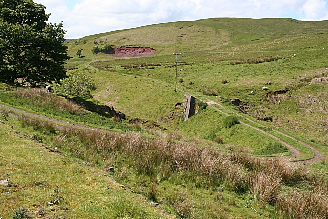 The trackbed of the narrow-gauge mineral railway at Evishacrow, with mine workings visible on the hillside beyond.