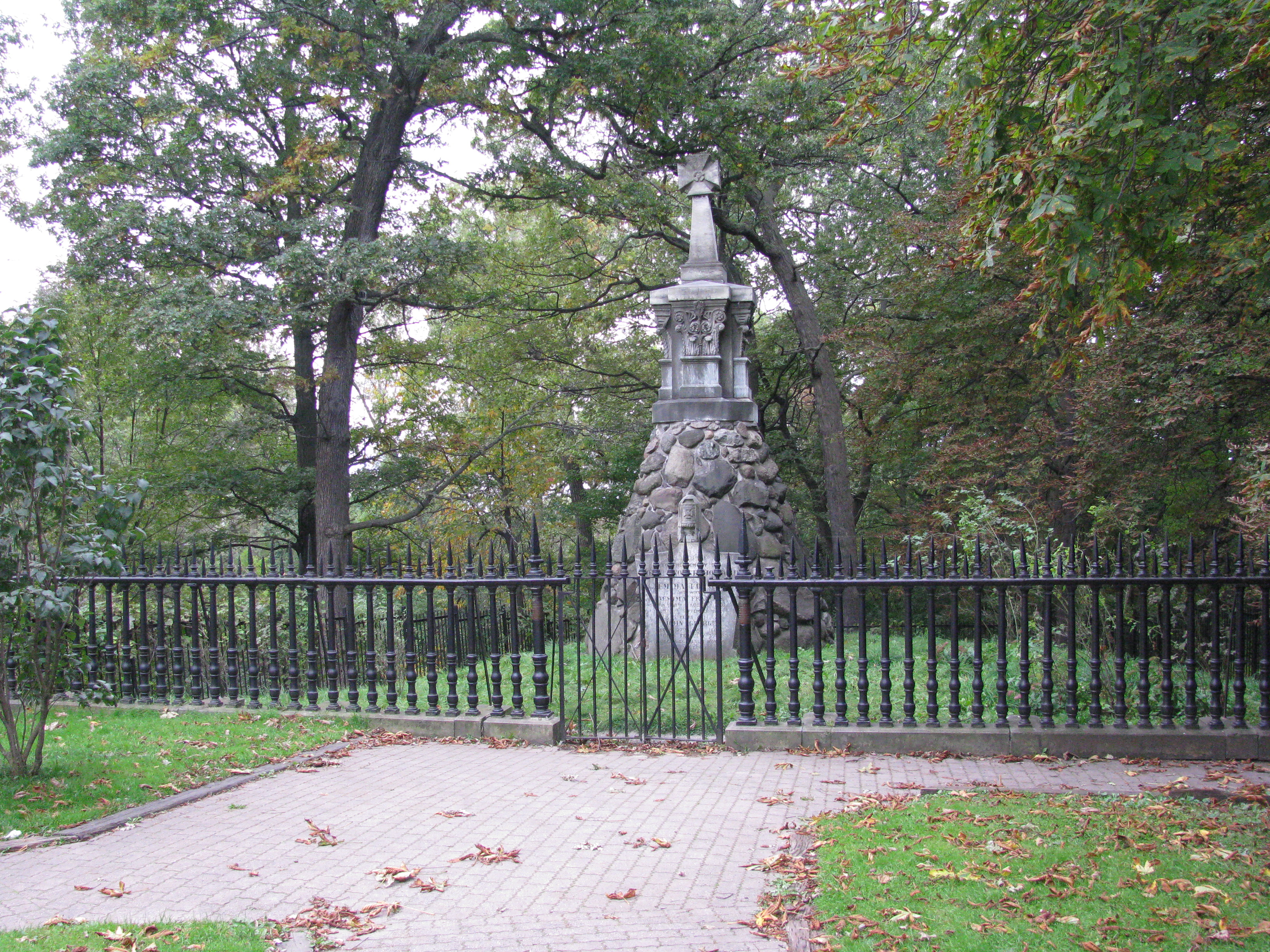 The wrought-iron railing enclosing the tomb of John and Jemima Howard in Toronto's High Park — a salvaged fragment of the 1710s St Paul's Cathedral churchyard railings cast at Gloucester Furnace, Lamberhurst.