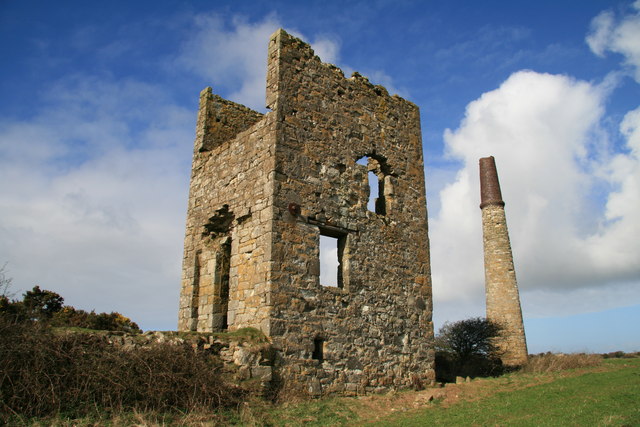 A ruined granite engine house and standing chimney stack in open Cornish farmland, the surviving surface remains of the former Ventonwyn stamps engine, part of the Great Dowgas Mine complex.