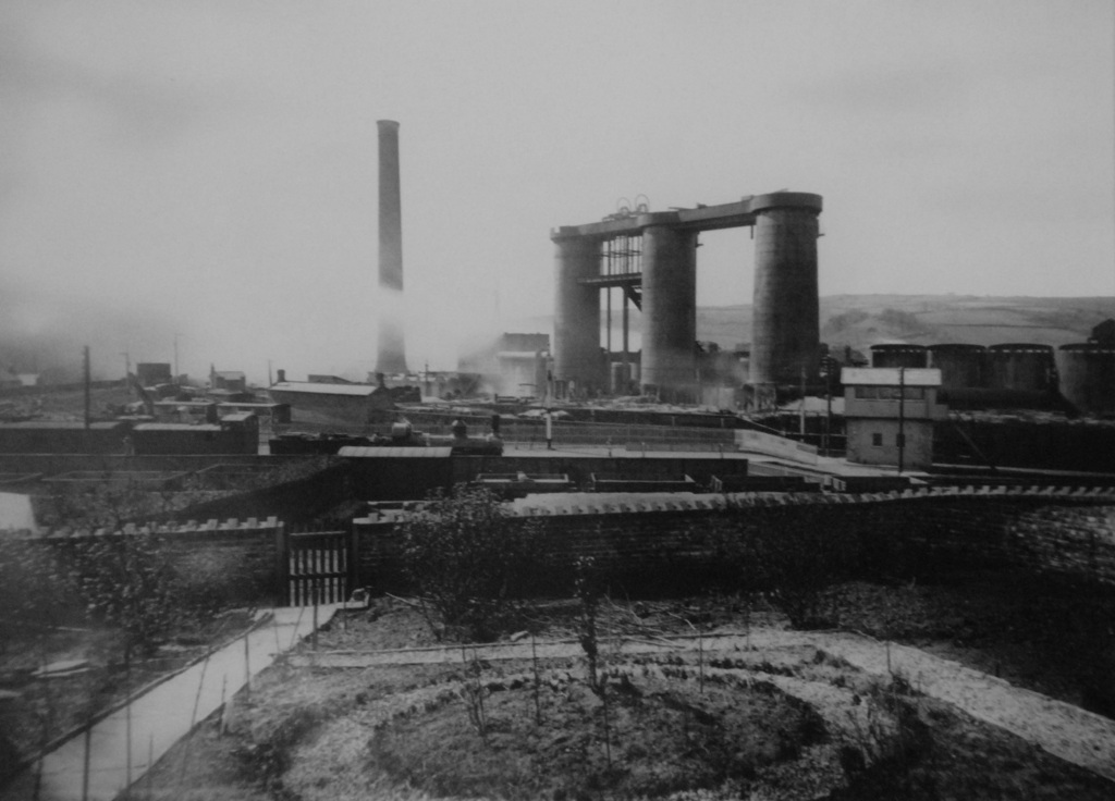 A view westward across Grosmont station showing the ironworks' three blast furnaces, engine house chimney, and a steam locomotive in the station foreground, photographed around 1880.