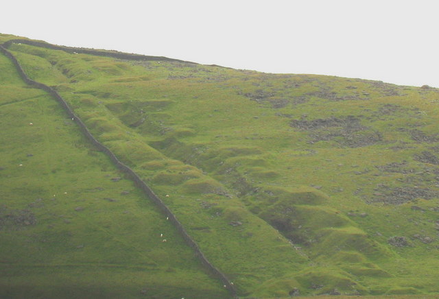 The narrow linear scar of Hafotty's manganese workings running up the grassed-over hillside north of Barmouth, following the steeply dipping ore bed.
