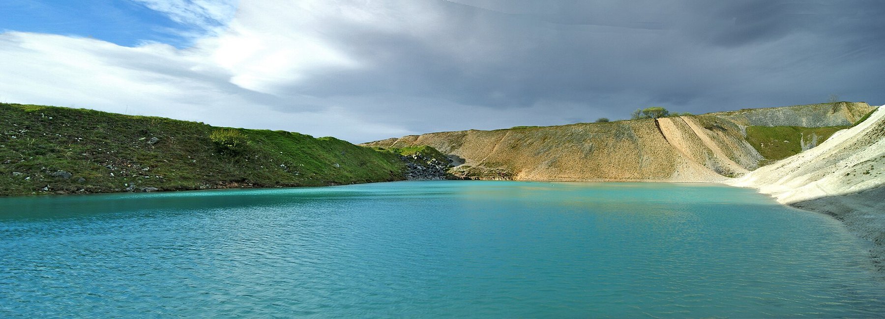 The flooded pit at Harpur Hill Quarry near Buxton, its water an opaque turquoise from suspended calcium carbonate, below pale grey limestone quarry faces