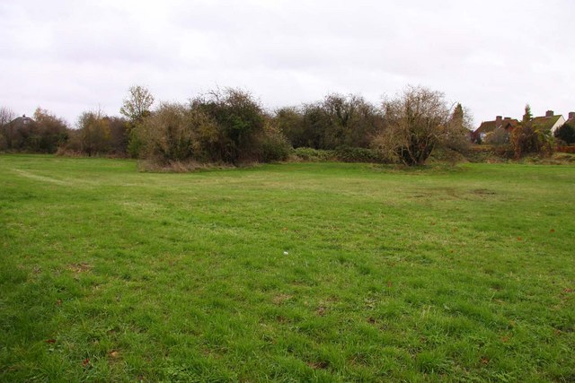 The grassed-over former quarry pit at Rock Edge, Headington, now a nature reserve — the underlying exposed limestone face is prized for its Jurassic coral-reef fossils.