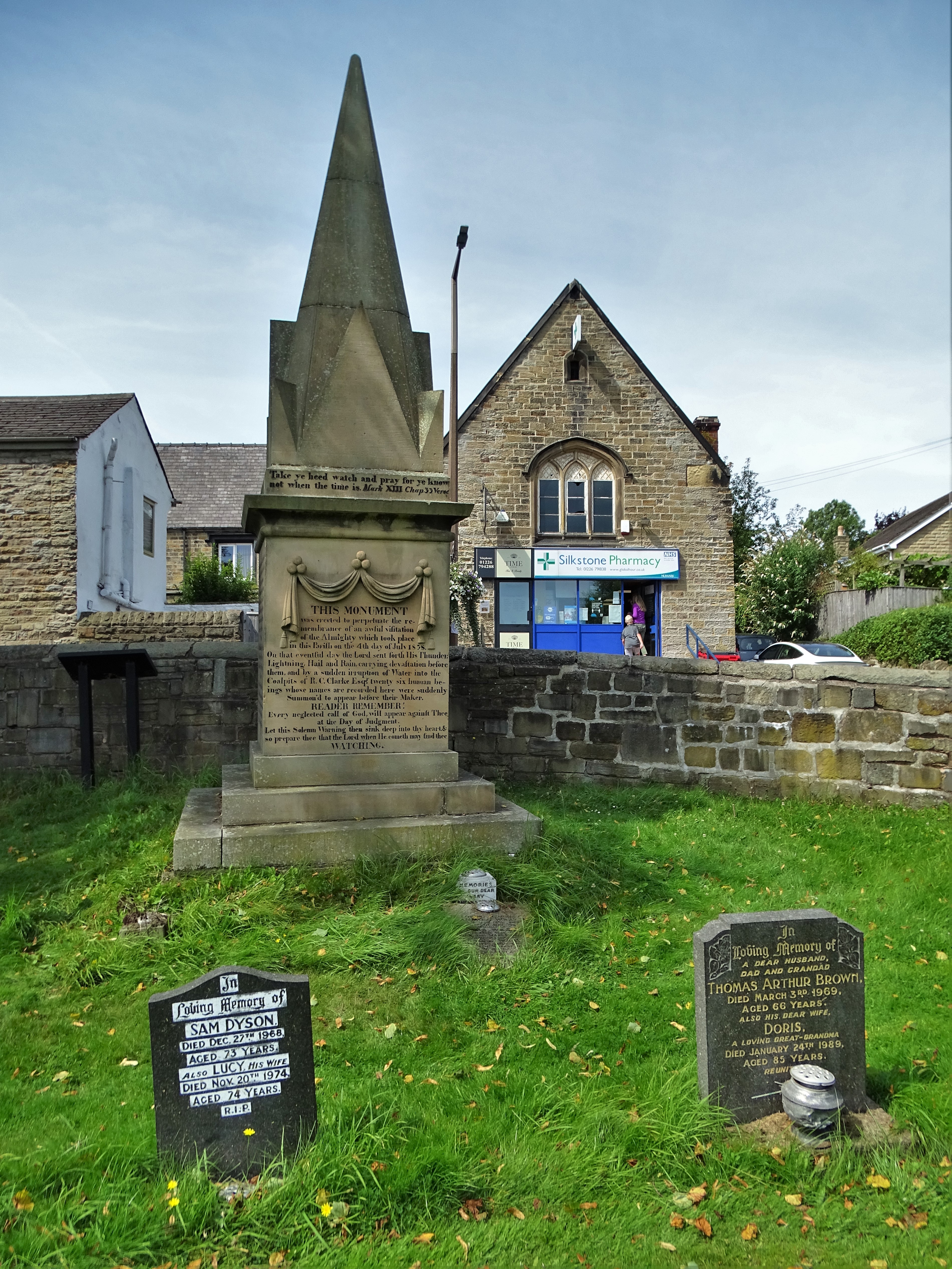 A tall stone pyramid-capped memorial in a churchyard, listing the names of children killed in the 1838 Huskar Pit disaster