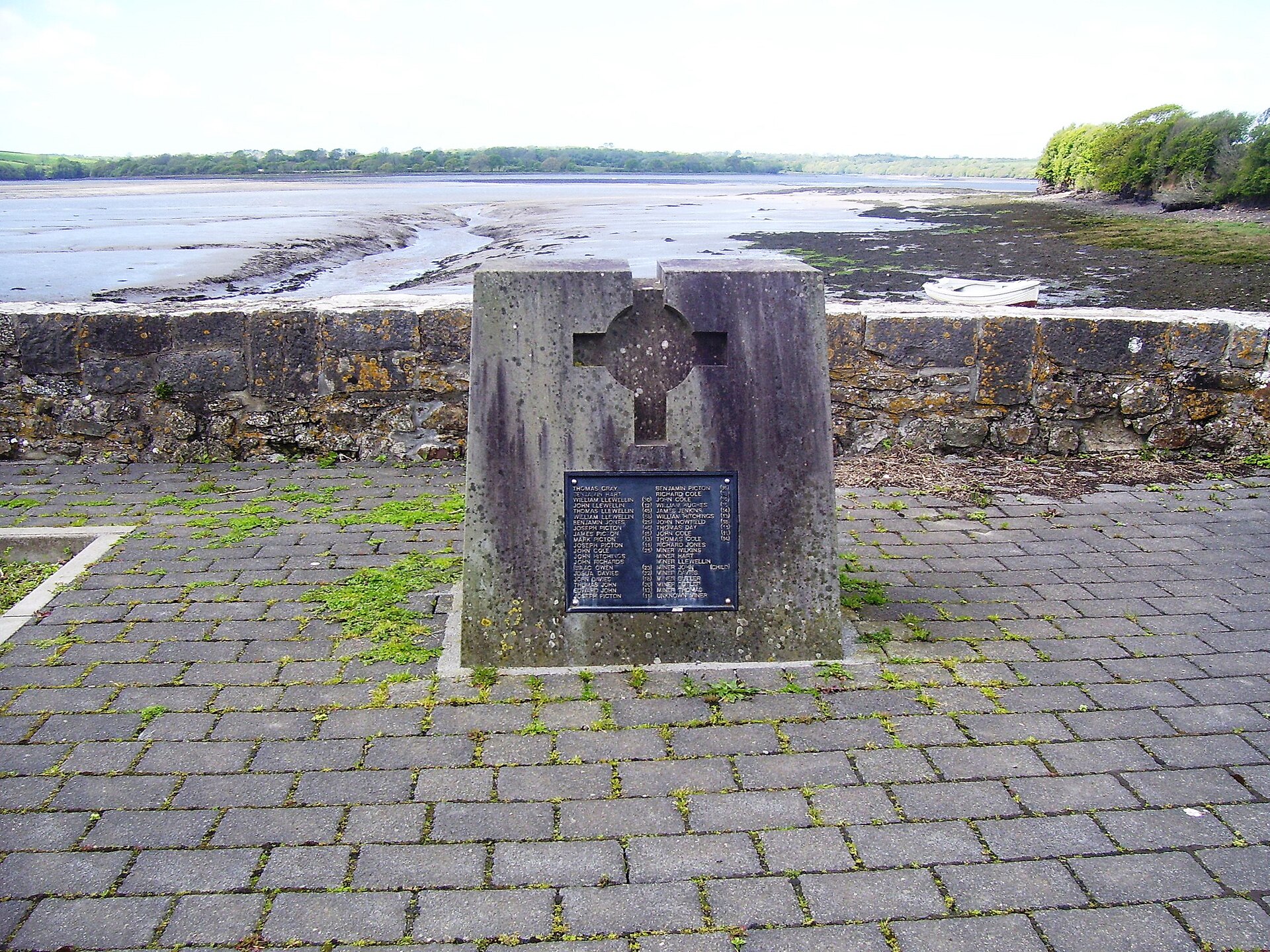 A stone memorial at Landshipping Quay bearing a plaque to those killed in the 1844 Garden Pit disaster, with the estuary behind.