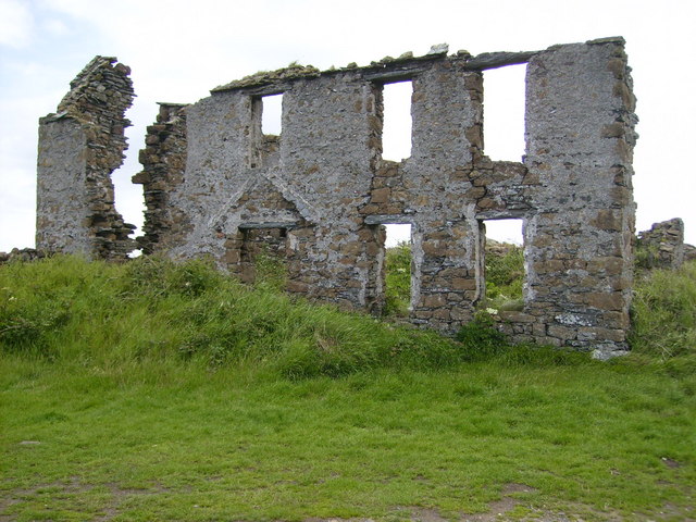 The front facade of a low stone building standing on the open grass of the Langness peninsula, believed to have served the mine that worked here