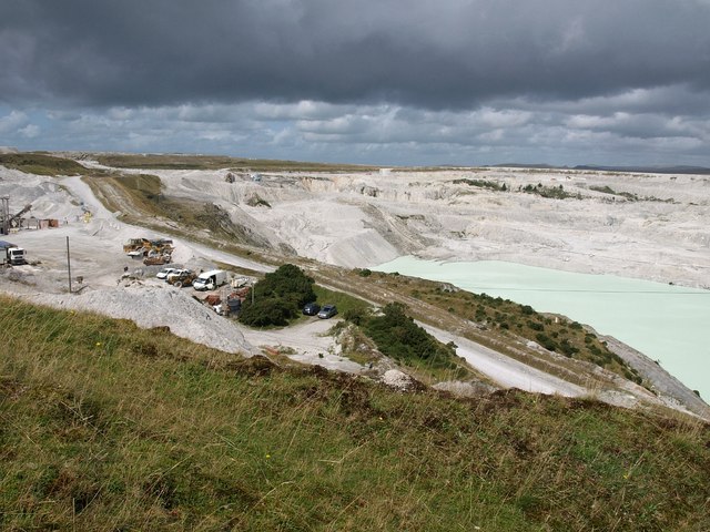 A large white china clay pit cut into the edge of Dartmoor, with worked faces and standing water.
