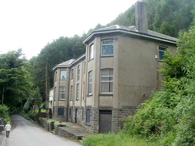 A long two-storey stone building, the former colliery offices at Llanbradach, seen from the road.