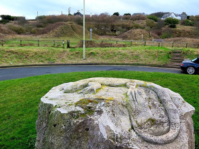 A grassed-over limestone quarry face above the coast at Marsden, with scrub growing along its foot