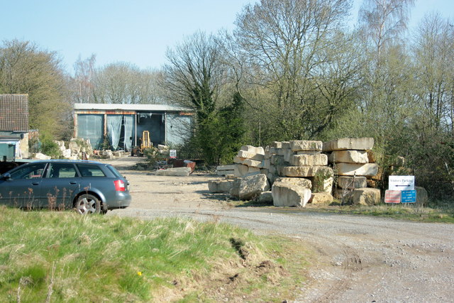 The surface yard of Monks Park Mine in 2008: stacked blocks of cut Bath stone beside a gravel track, a car and an open-fronted shed