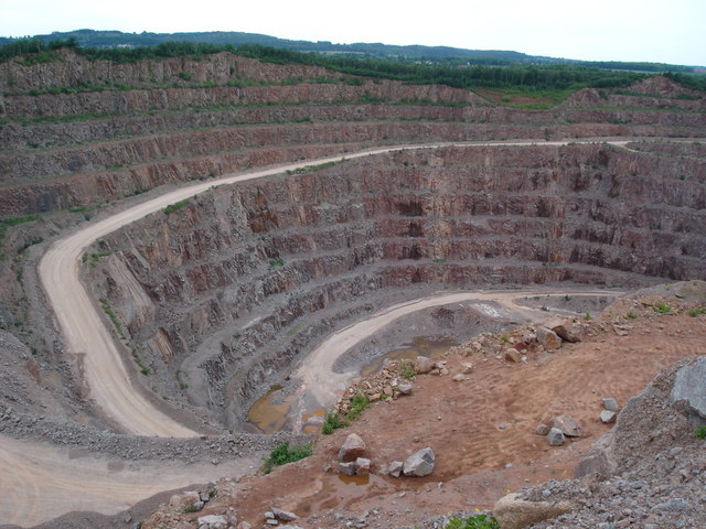 Looking down into Buddon Quarry, Mountsorrel — one of the largest hard-rock granite quarries in Britain, its terraced pit walls giving a sense of scale against the small vehicles working the quarry floor.