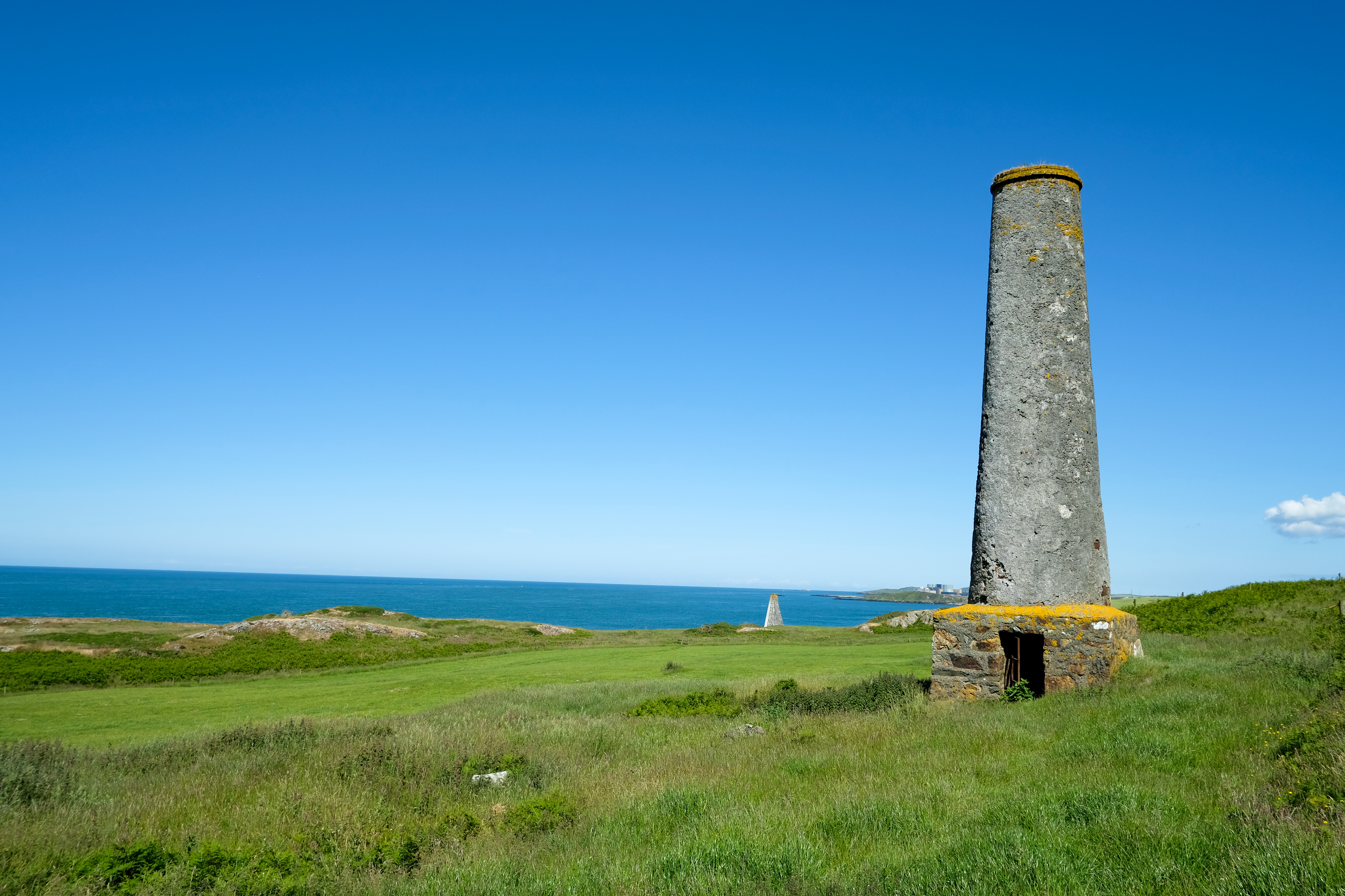 The surviving 19th-century chimney at Carmel Head Copper Mine, on the cliffs above the sea.