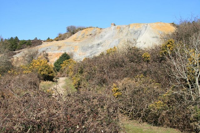 A large, colourful spoil heap ('burrow') at Nangiles Mine, with the top of the ruined 1862 engine house just visible near the centre of the heap.
