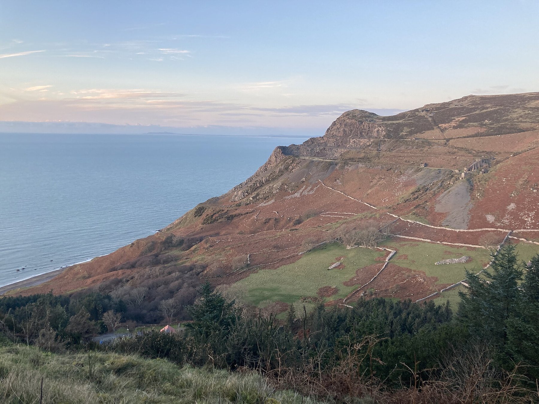 The abandoned granite workings on the steep hillside above Nant Gwrtheyrn on the Llŷn peninsula, with quarry terraces cut into the slope above the sea