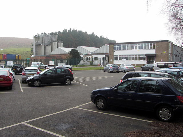 A factory with silos and a car park below a wooded hillside on the former colliery site