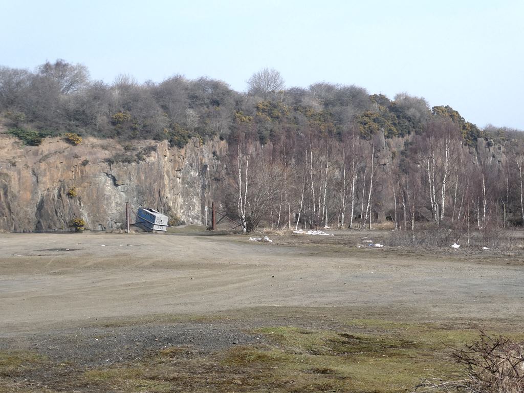 The flooded workings of Prestonhill Quarry at Inverkeithing, deep green water enclosed by the bare dolerite cliffs left by quarrying