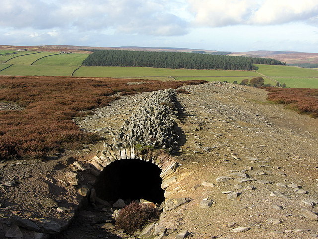 A long low ridge of stone and turf running away across rough moorland, the collapsed line of a smelt mill flue.