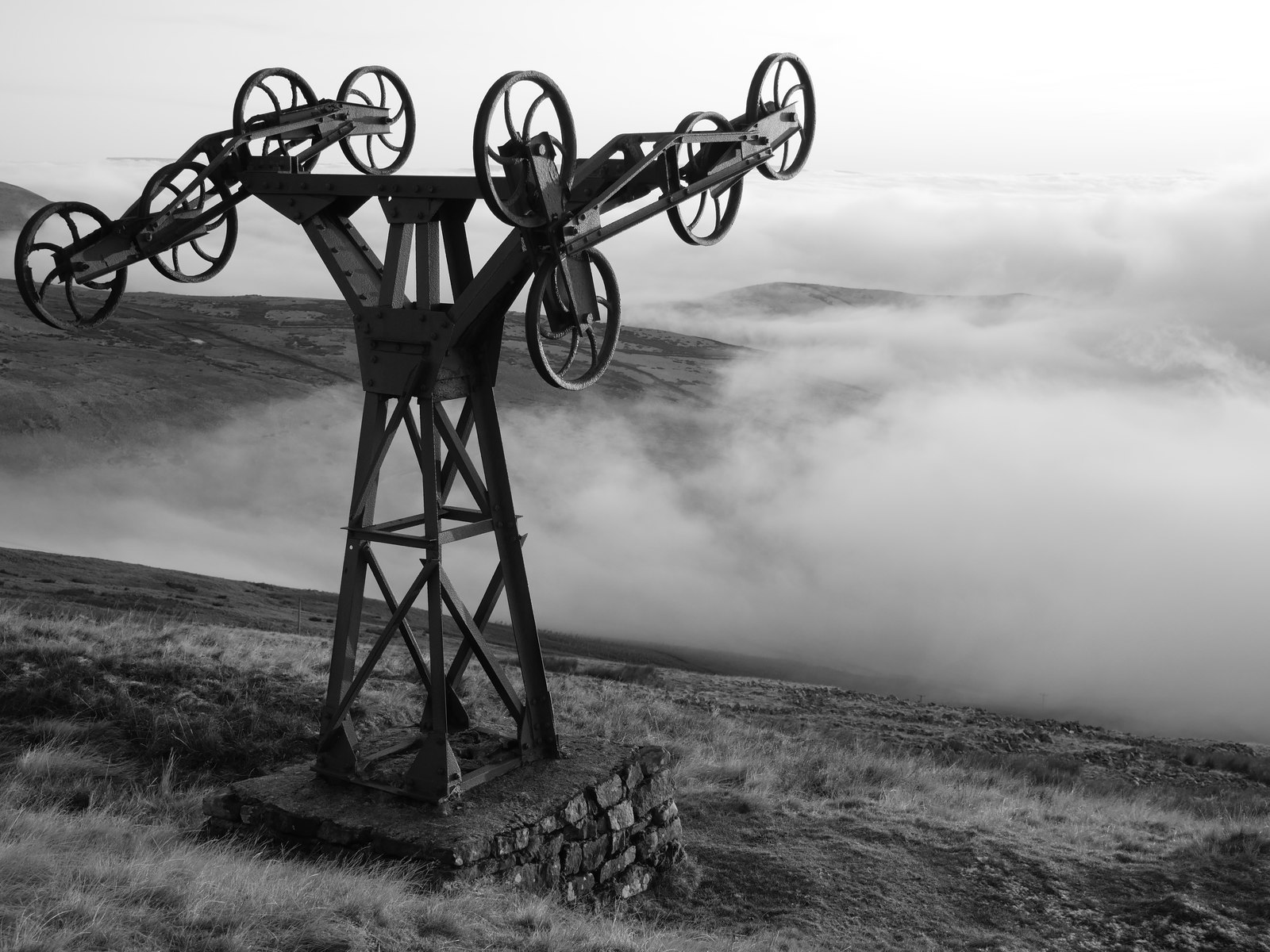 A surviving iron pylon from the Silverband Mine aerial ropeway standing on the lower slopes of Great Dun Fell, with the fellside and sky visible behind it.
