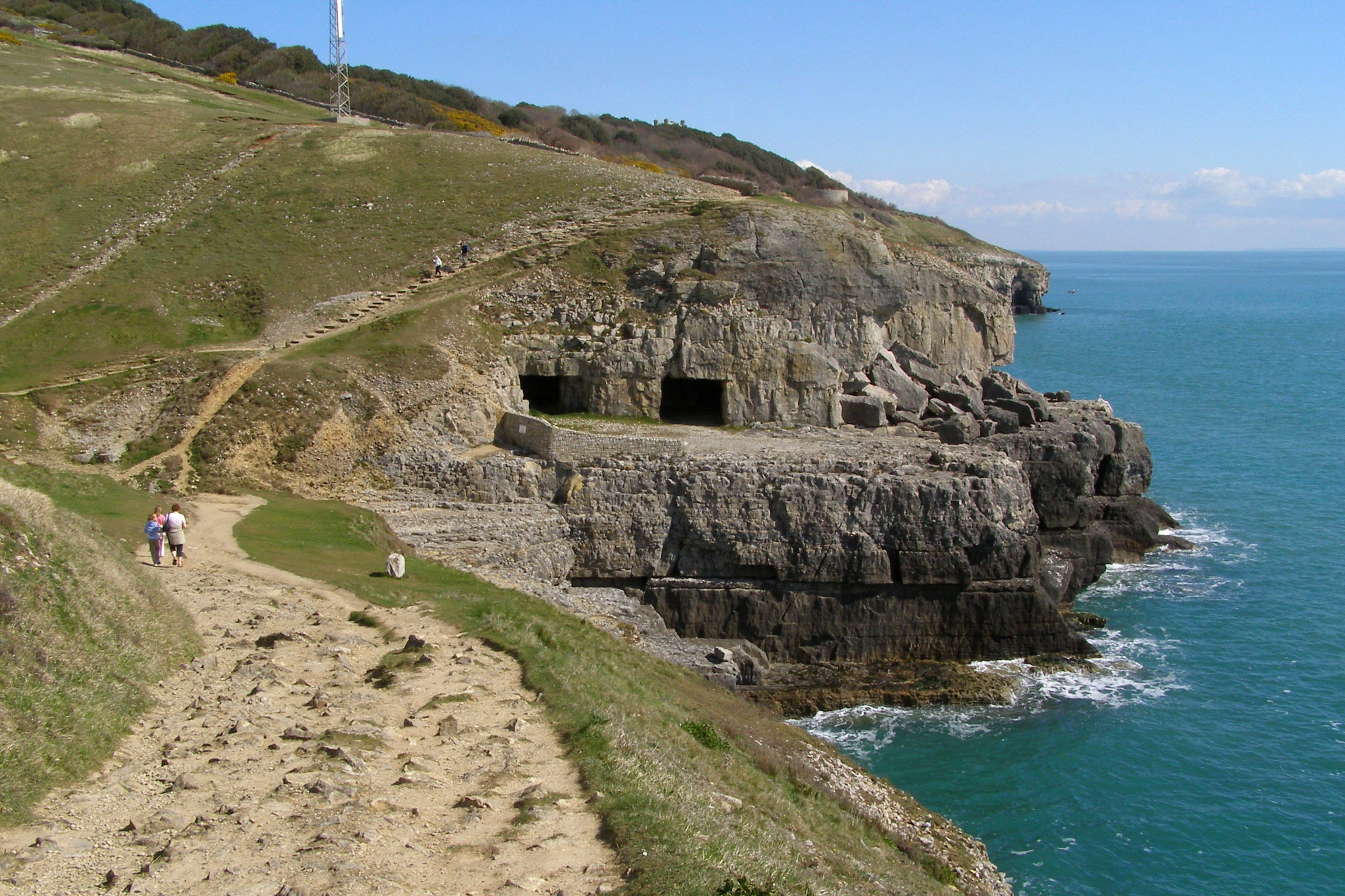 The quarried cave mouths of Tilly Whim, cut horizontally into the Purbeck coastal cliffs near Swanage, seen from the South West Coast Path.