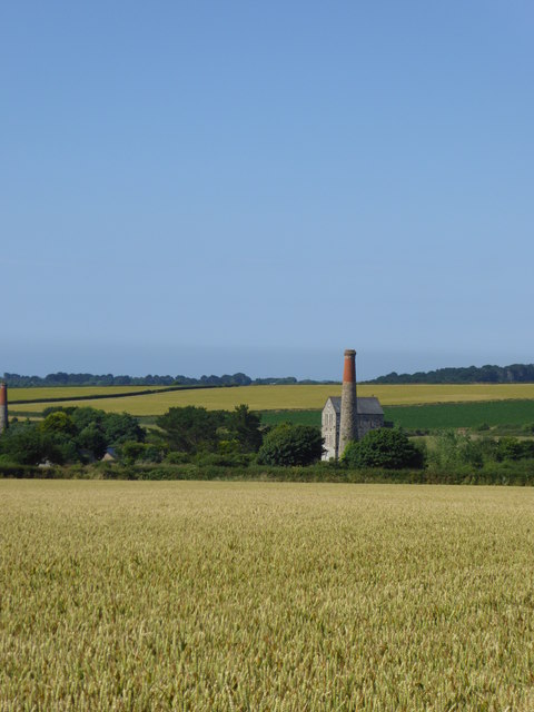 The tall granite and stone engine house of the mine, now converted to a dwelling, standing above the Cornish fields