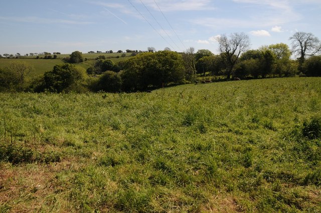 Green farmland with hedgerows and trees, no surface remains visible.