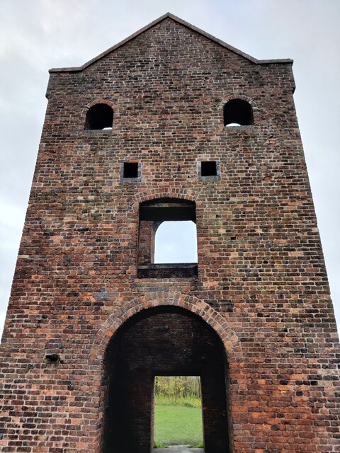 The tall brick gable of a roofless engine house, with a round-arched bob portal high in the wall and a larger arched opening at ground level.