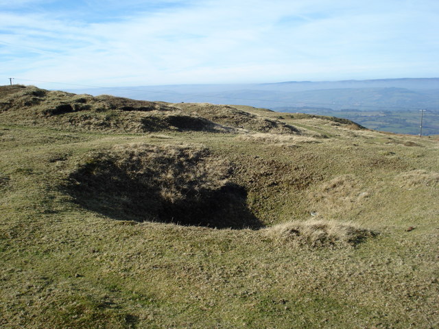 The circular depression and spoil ring left by a collapsed bell pit on Clee Burf in Shropshire, one of many early mining pits in the area.