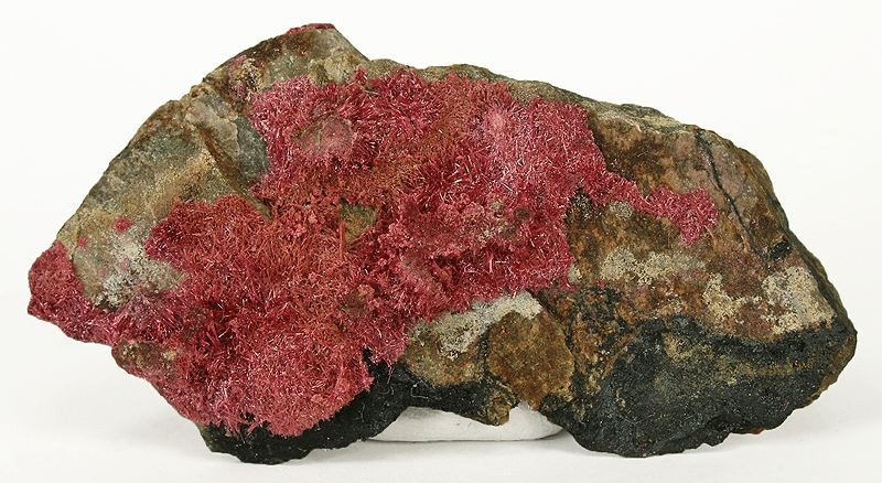 Erythrite, a secondary cobalt arsenate mineral known as 'cobalt bloom', which forms as a pink-red coating on weathered cobalt ores — a mineralogical reminder of how closely cobalt and arsenic occur together.