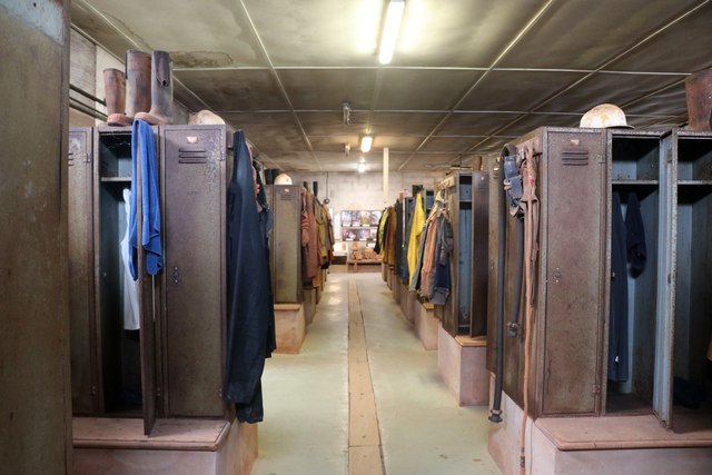 Rows of lockers and hanging clothes preserved in the miners' dry at Geevor Tin Mine, Cornwall.