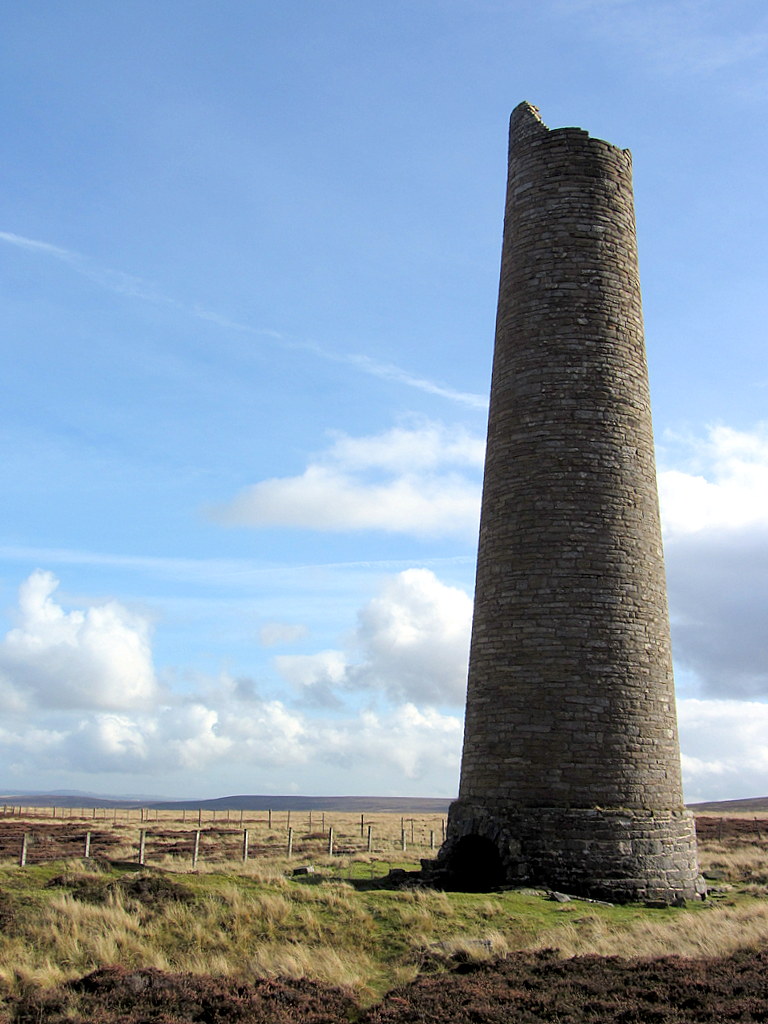 A stone chimney at the head of a lead smelt mill flue on open moorland near Sikehead Dam.