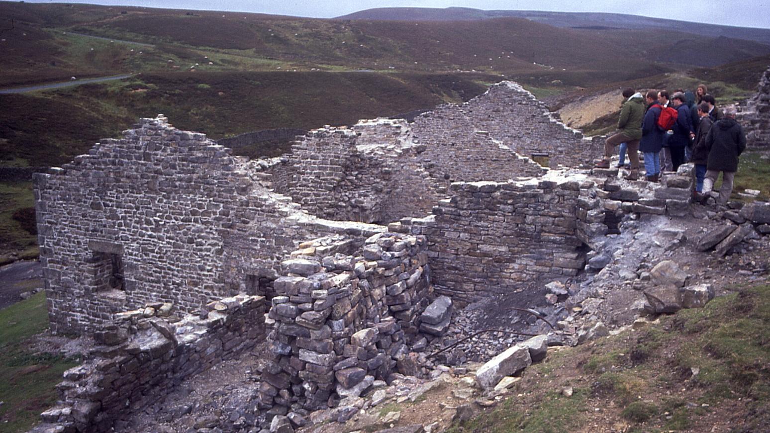 The ruined stone buildings of Surrender lead smelt mill in a Swaledale valley bottom.