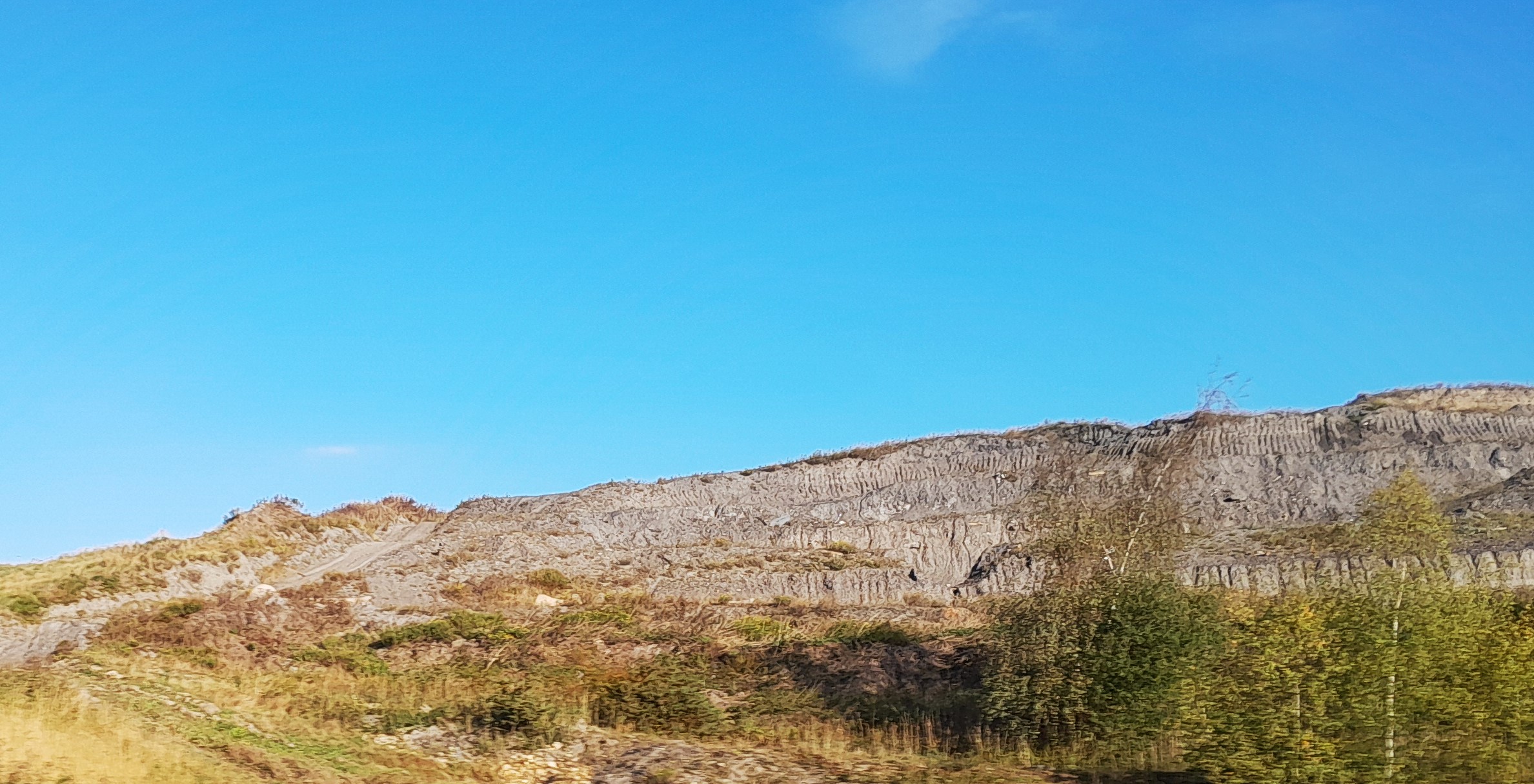 A weathered, partly vegetated colliery spoil heap near Stainforth, South Yorkshire, its eroded slopes exposing the dark waste rock and shale tipped there over the mine's working life.