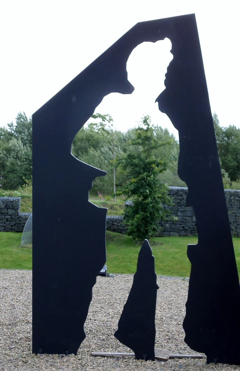 A tall black steel panel cut so that the empty space through it forms the outline of a standing miner.