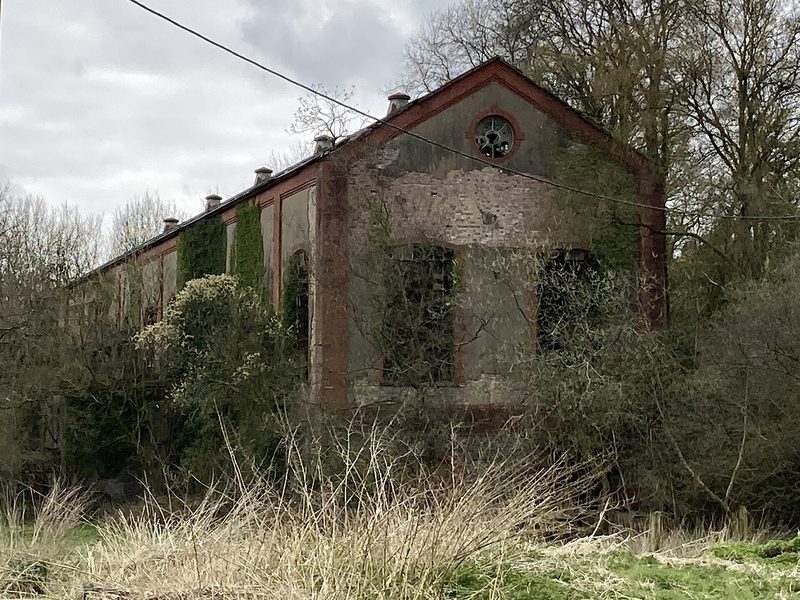 A long two-storey rendered industrial hall with rows of arched brick-framed windows and a slate roof.