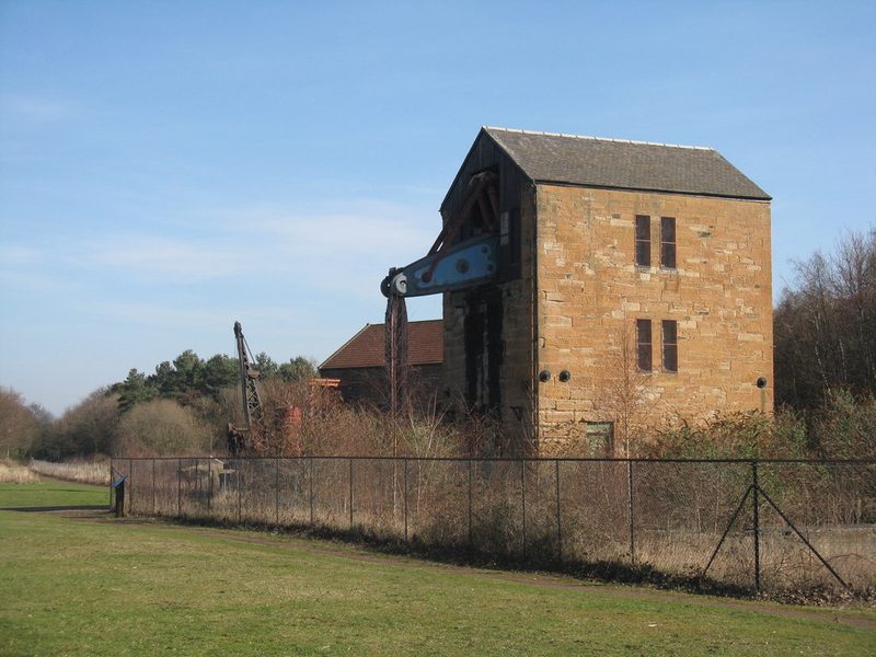 A tall engine house with a large iron beam projecting from its upper wall.