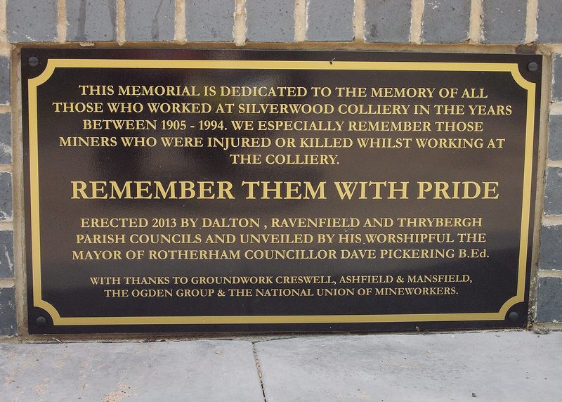 A black memorial plaque with gold lettering remembering those who worked at and were killed at Silverwood Colliery.