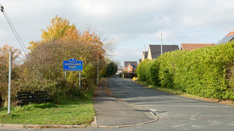 The road into the small settlement of Auckland Park east of Bishop Auckland, with its blue and yellow County Durham sign.