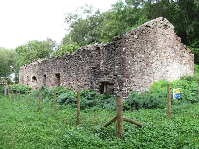 The roofless stone shell of Augill smelt mill standing in rough pasture beside Augill Beck.