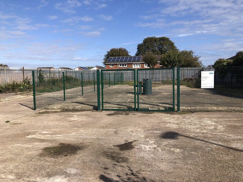 A green mesh fence around a concrete compound on the former Bedlington A pithead site, with houses behind.