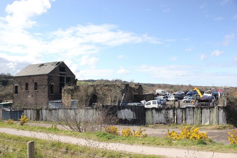 Roofless brick and stone colliery buildings standing in rough ground on the Dee estuary shore at Bagillt